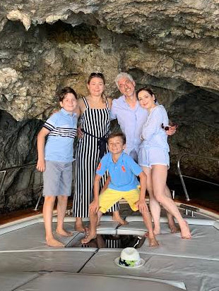 A family of five gathered on a boat inside a rocky coastal cave.
